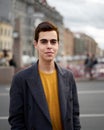 Handsome stylish fashionable man, brunette in elegant gray coat, stands on street in historical center of St. Petersburg. Young Royalty Free Stock Photo