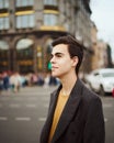 Handsome stylish fashionable man, brunette in elegant gray coat, stands on street in historical center of St. Petersburg. Young Royalty Free Stock Photo