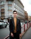 Handsome stylish fashionable man, brunette in elegant gray coat, stands on street in historical center of St. Petersburg. Young Royalty Free Stock Photo