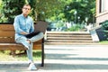 Handsome stylish freelancer sitting on the bench with laptop