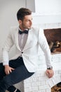 Handsome stylish man in elegant suit sitting near fireplace