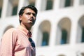 Handsome stylish man outdoors, with striped shirt. Sunglasses not worn. Building in the background