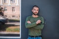 Handsome stylish man is standing near wall.