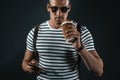 Handsome stylish man in sunglasses using smartphone while drinking coffee and looking at camera Royalty Free Stock Photo