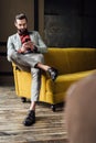 handsome stylish man using smartphone and sitting on yellow Royalty Free Stock Photo