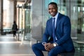 Handsome and stylish modern african american business man entrepreneur executive, sitting outside of office with cheerful smile Royalty Free Stock Photo