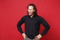 Handsome stylish young curly long haired man in black shirt posing isolated on red wall background studio portrait Royalty Free Stock Photo