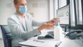 Handsome Stylish Young Man Wearing Protective Face Mask Uses Hand Sanitizer while Working at His D Royalty Free Stock Photo