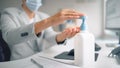 Handsome Stylish Young Man Wearing Protective Face Mask Uses Hand Sanitizer while Working at His D Royalty Free Stock Photo