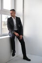 Handsome successful man in a black classic suit looks out the window. portrait of a gray-haired man Royalty Free Stock Photo