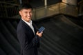 Handsome Asian businessman holding his smartphone while walking down the stairs in a city Royalty Free Stock Photo