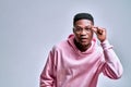 A handsome surprised african american is holding glasses and is shocked by what he saw in the studio on a gray background Royalty Free Stock Photo