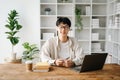 Handsome and talented young Asian man student working on his project assignment, using laptop and tablet to search an online Royalty Free Stock Photo