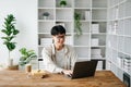 Handsome and talented young Asian man student working on his project assignment, using laptop and tablet to search an online Royalty Free Stock Photo