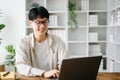 Handsome and talented young Asian man student working on his project assignment, using laptop and tablet to search an online Royalty Free Stock Photo