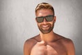 Handsome tanned man with trendy hairdo, bristle, standing topless, demonstrating his muscular body, wearing sunglasses, having ple