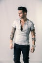 Handsome tattooed young man wearing grey t-shirt, standing