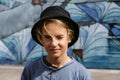 handsome teenage boy in hat osing at urban graffiti waal in hat