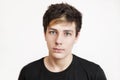 A handsome teenage boy with a sad face on a white background. Portrait of an angry teen in a black shirt Royalty Free Stock Photo