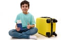 Handsome teenage boy traveler with boarding pass and suitcase, showing thumb to camera, traveling abroad for the weekend Royalty Free Stock Photo