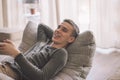 Handsome teenage guy relaxing on modern soft couch at home in living room