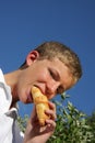 Handsome teenager biting into a croissant