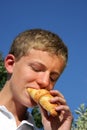 Handsome teenager biting into a croissant