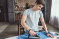 handsome teenager ironing blue shirt