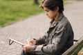 Handsome teenager painting something in his notepad outdood during the break. Talanted young boy