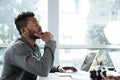 Handsome thinking serious young man sitting in office coworking