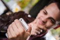 Handsome thoughtful young man holding smart phone and looking at it while sitting in cafe outdoors. Selective focus. Royalty Free Stock Photo