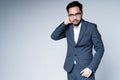 Handsome tired asian businessman wearing glasses in a jacket and trousers rubs his neck with his hand Royalty Free Stock Photo