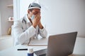 Handsome tired doctor in white uniform sitting at the work desk while closing nose with hands Royalty Free Stock Photo