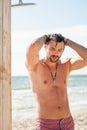 Handsome topless man taking a shower on the beach