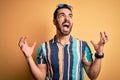 Handsome tourist man with beard on vacation wearing summer striped shirt and sunglasses crazy and mad shouting and yelling with Royalty Free Stock Photo