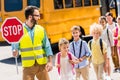 handsome traffic guard crossing road with pupils in front of Royalty Free Stock Photo