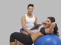 Handsome trainer with a women on ball