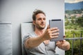 Handsome trendy man looking down at a tablet computer, outdoor Royalty Free Stock Photo