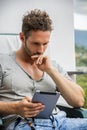 Handsome trendy man looking down at a tablet computer, outdoor Royalty Free Stock Photo