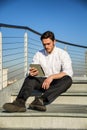 Handsome trendy man looking down at a tablet computer, outdoor Royalty Free Stock Photo