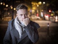 Handsome trendy young man, standing on a sidewalk at night