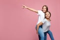 Handsome two young twin sisters with beautiful smile pointing finger away over pink background. Text space. Royalty Free Stock Photo