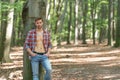 Handsome unshaven man with lumbersexual look in unbuttoned lumberjack shirt forest background Royalty Free Stock Photo