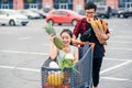 Handsome vietnamese man holds paper bags with food pushing in front of him shopping trolley with his happy beautiful Royalty Free Stock Photo