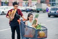 Handsome vietnamese man holds paper bags with food pushing in front of him shopping trolley with his happy beautiful Royalty Free Stock Photo