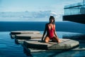 Handsome view of girl relaxing at swimming pool with ocean at background. Cute young woman in red bikini posing Royalty Free Stock Photo