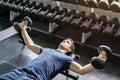 Handsome weightlifter lifting bench press working out with dumbbell in the gym