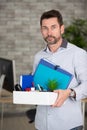 handsome worker leaving office taking box