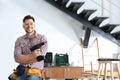 Handsome working man with screwdriver indoors, space for text. Home repair