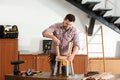 Handsome working man repairing wooden stool